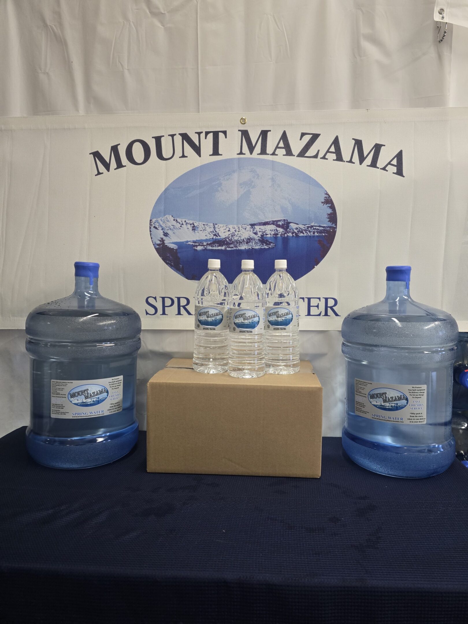 Two large water jugs, three small bottles, and a box labeled Mount Mazama Spring Water.