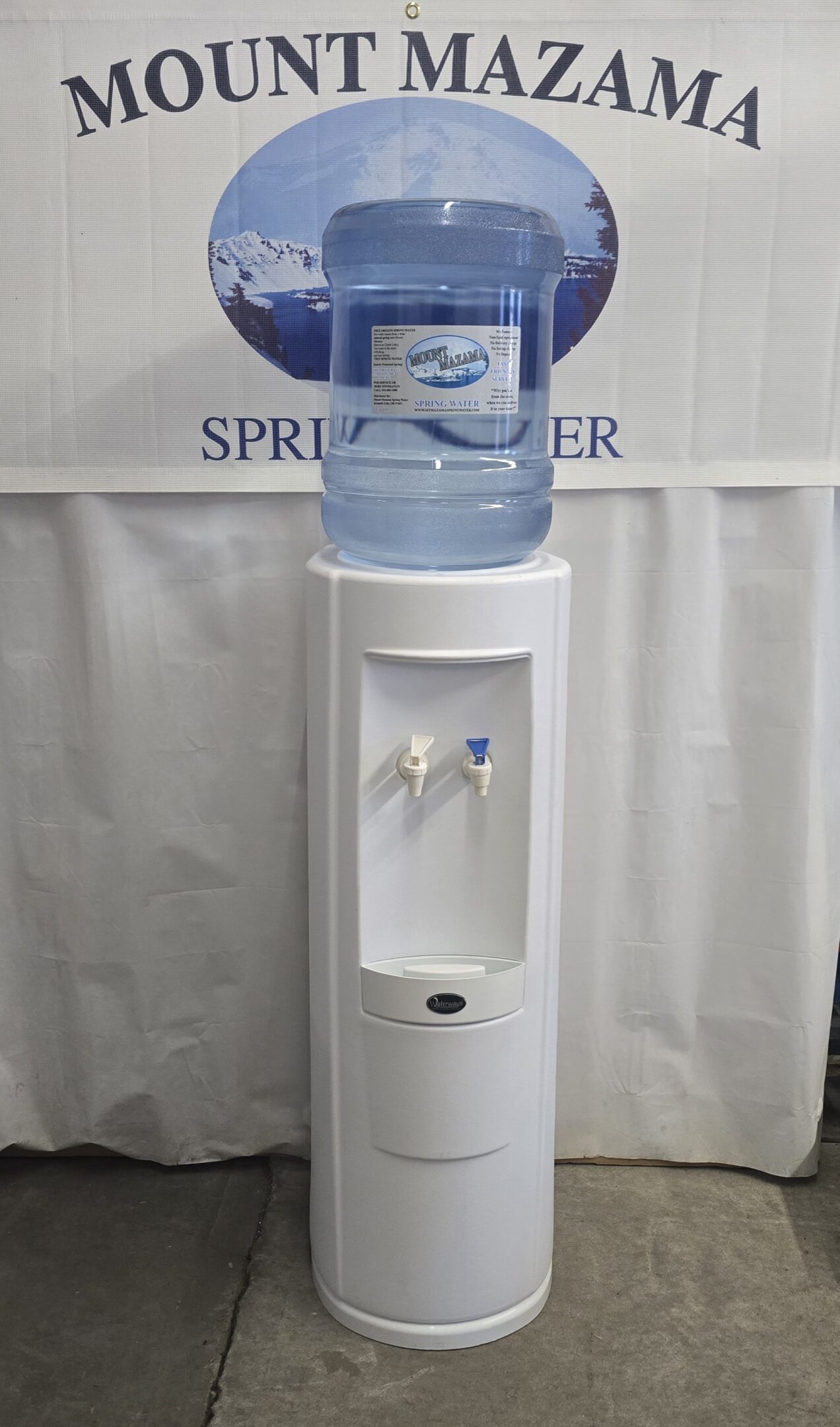 White water dispenser with two taps and a large water bottle on top.