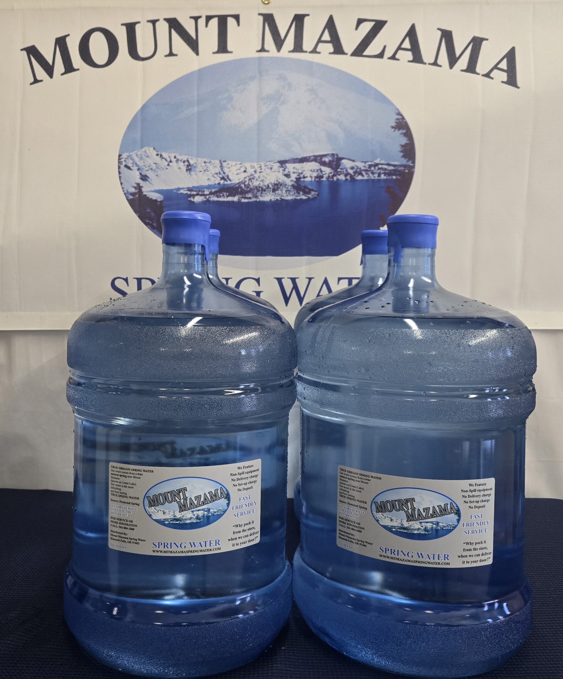Two large water containers with blue caps in front of a branded backdrop.