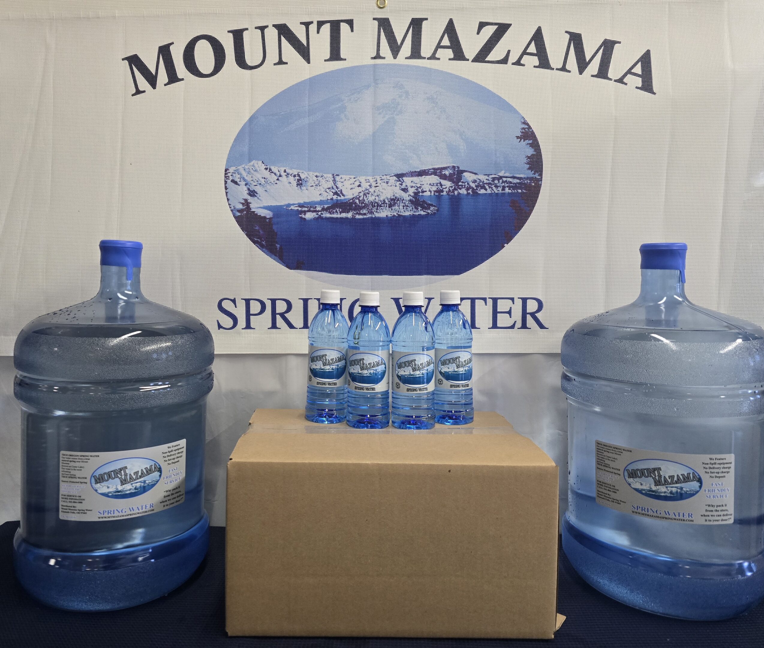 Water bottles and large jugs displayed in front of a Mount Mazama Spring Water sign.